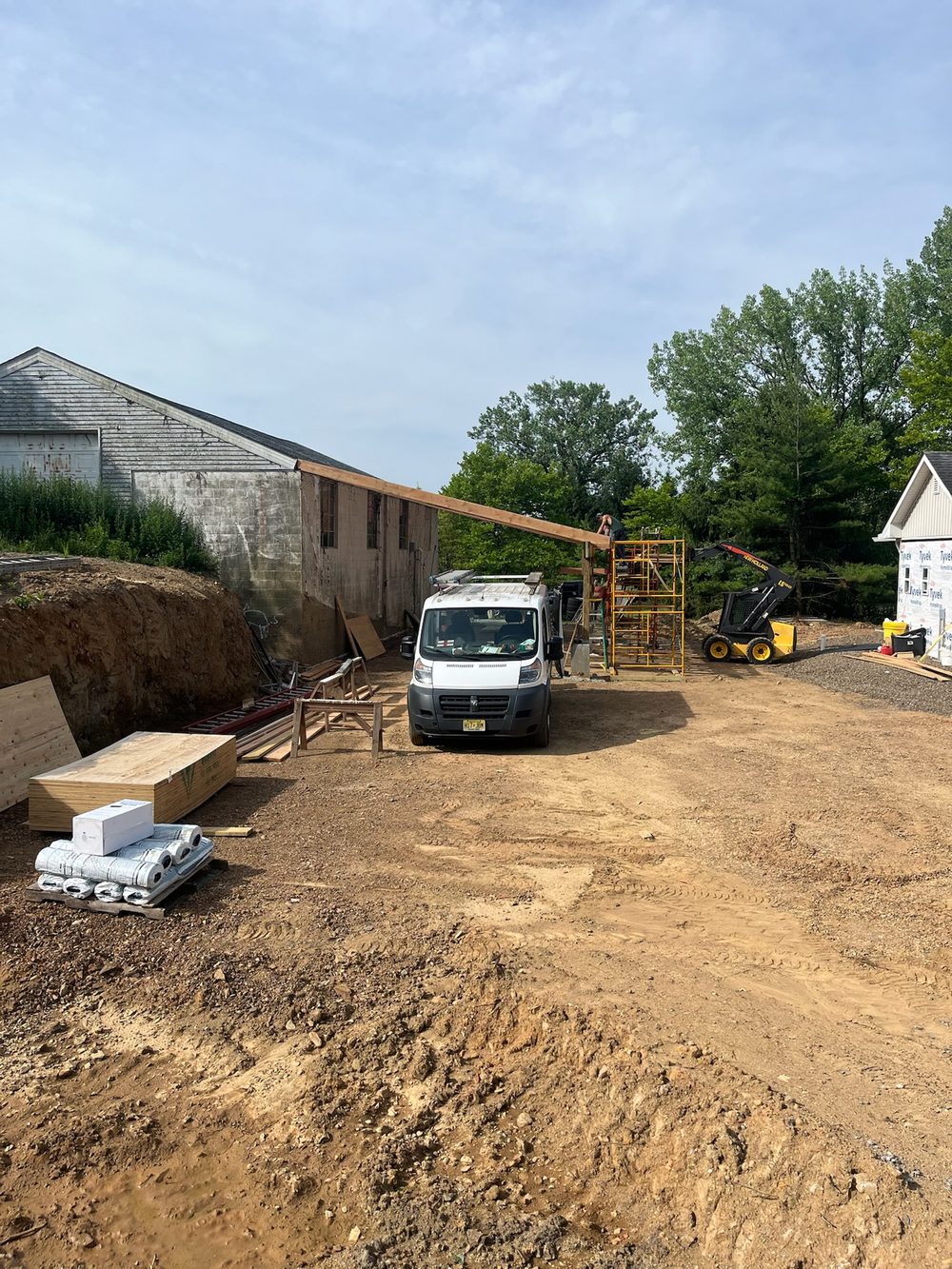 Commercial site prep with a skid steer and graded lot, staged for base and paving by Beckage in NJ