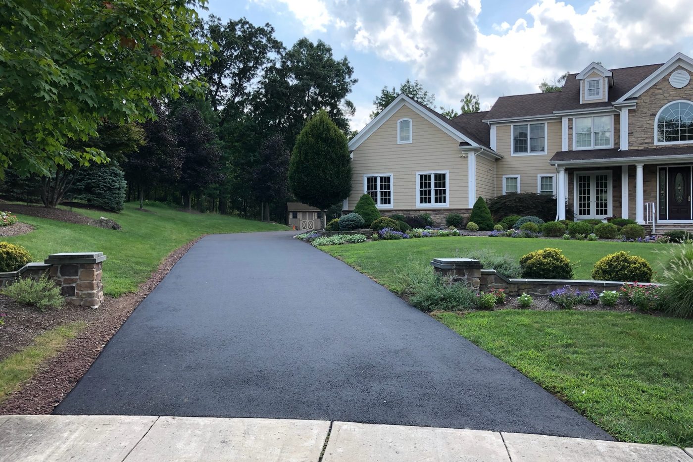 Freshly paved black asphalt residential driveway leading to a landscaped NJ home, completed by Beckage