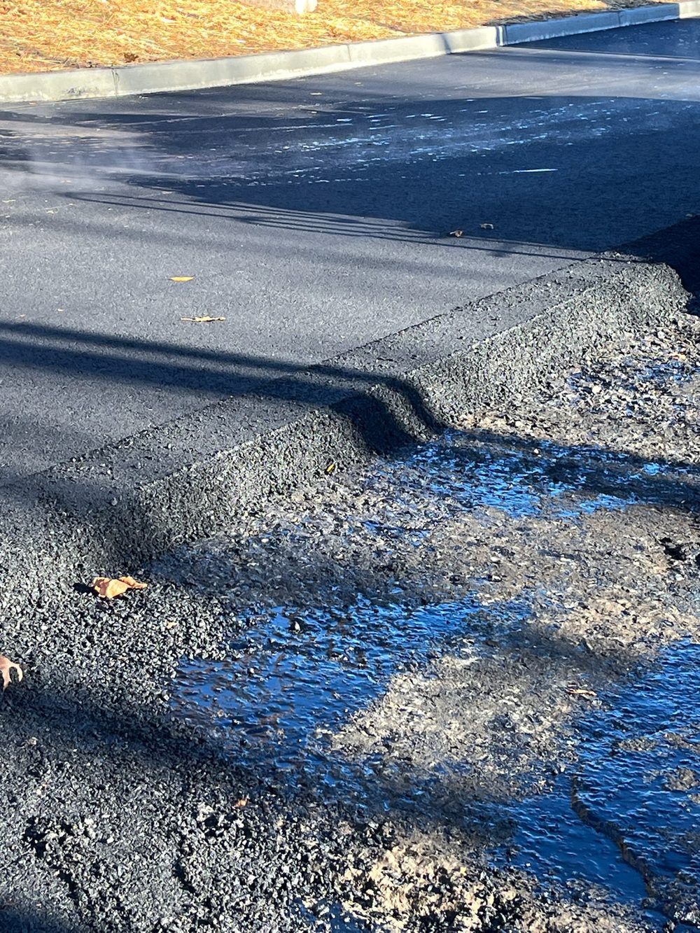 Close-up of a freshly laid asphalt mat edge compacted against the surrounding pavement on a NJ mill-and-pave job