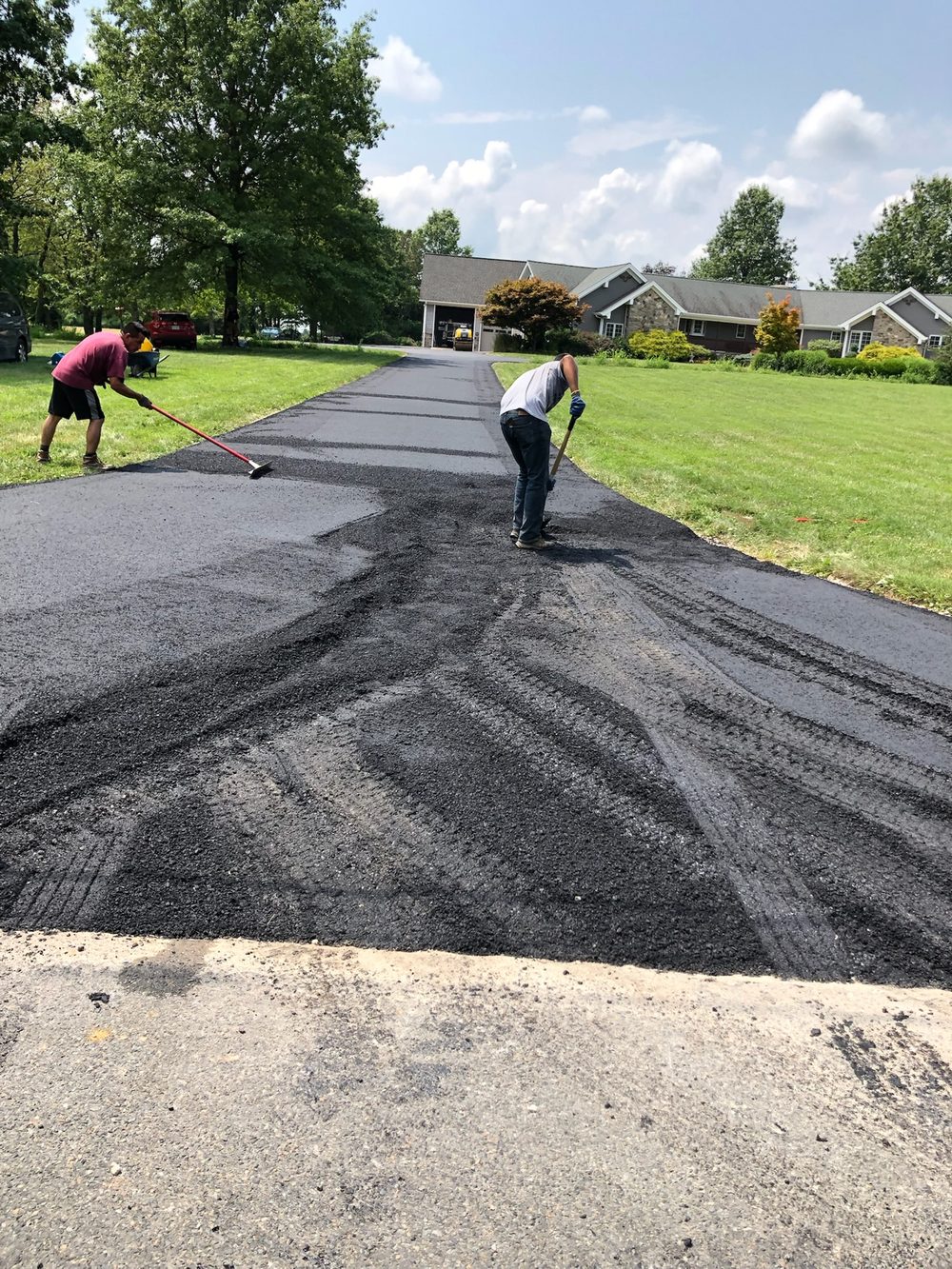 Beckage crew raking hot asphalt on a long residential driveway leading to a NJ home