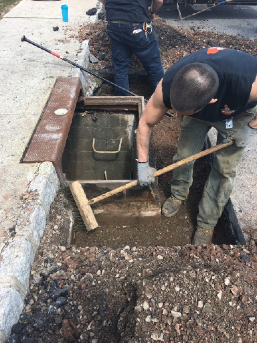 Beckage Sealcoating crew resetting a storm drain structure to grade in an excavated commercial curb line in NJ