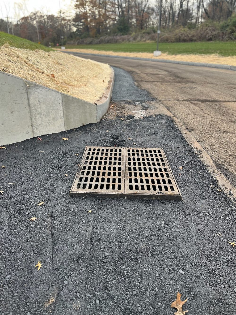 Concrete curb line and cast-iron catch basin set to grade in a new asphalt apron so runoff is carried off the lot, Beckage Sealcoating in New Jersey