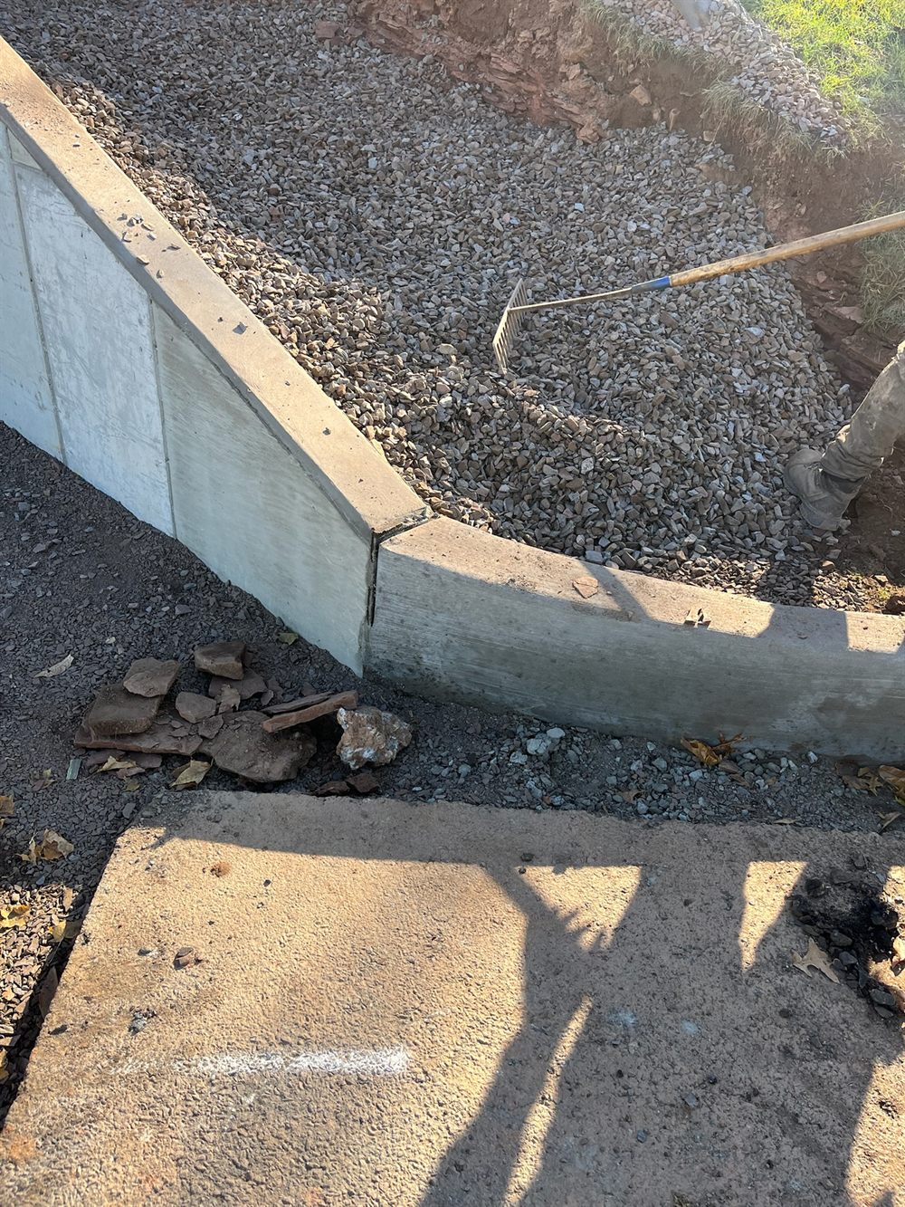 Newly poured concrete curb transitioning from a straight barrier section into a curved radius, with compacted stone base backfilled behind it, by Beckage Sealcoating in NJ